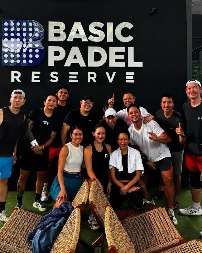 Large group posing under the Basic Padel Reserve sign
